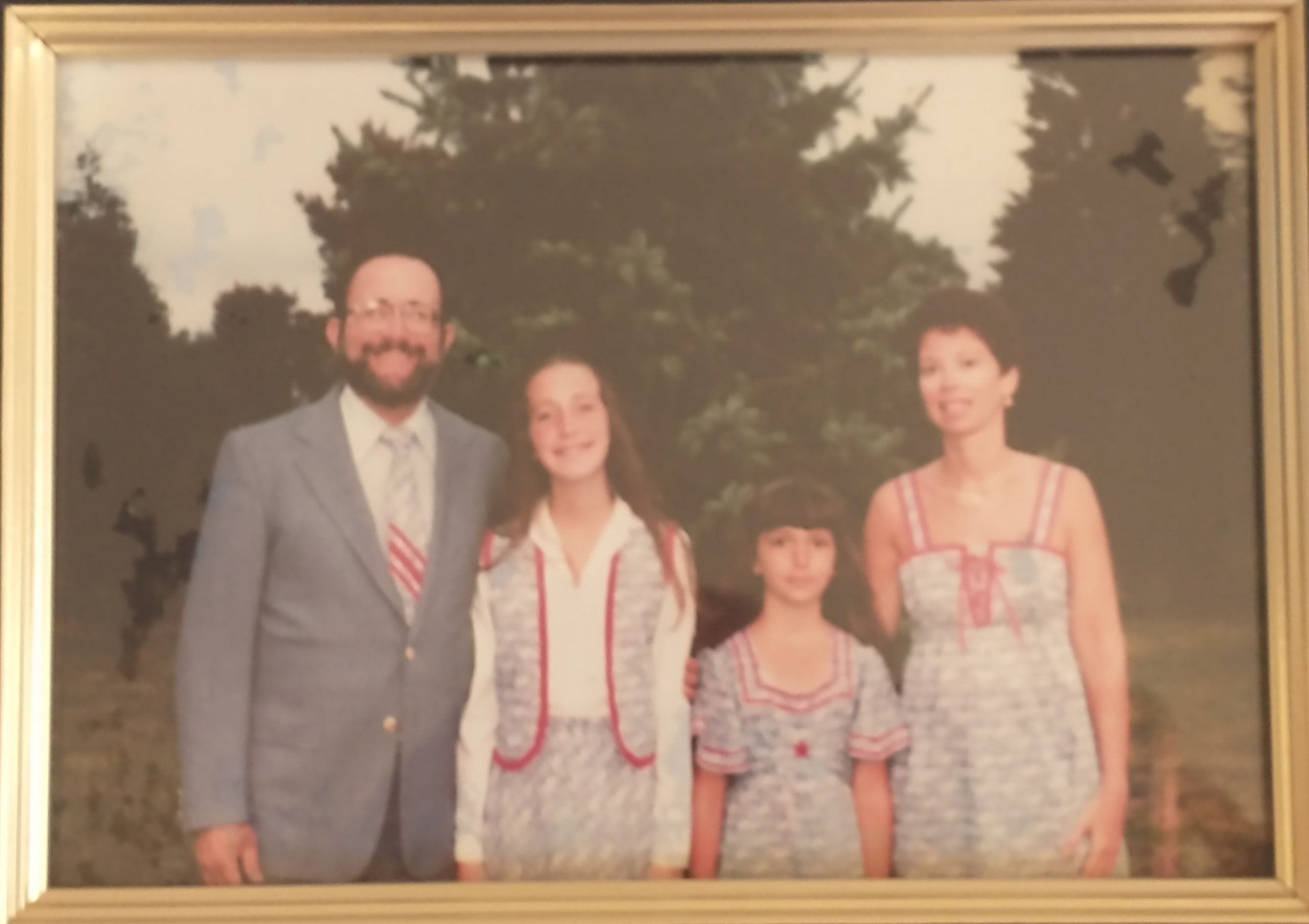 A very faded vintage-1970s photo of my family - father, sister, mother, and me - all dressed in matching outfits as described in the text.