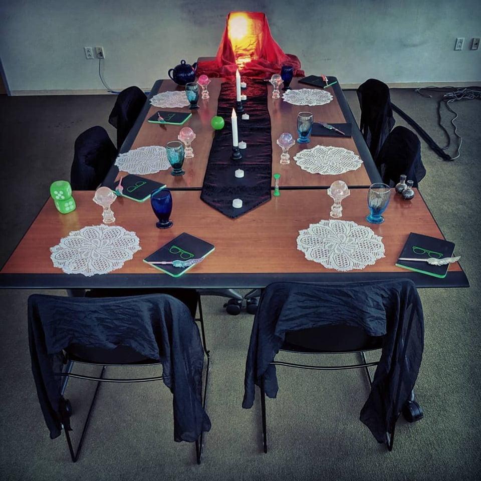 conference room table decorated with black scarves, crystal balls, goblets, candles, and a glowing red lamp