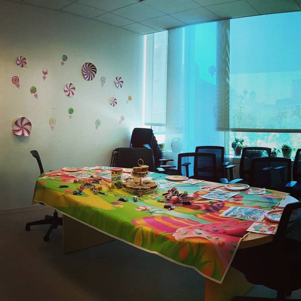 A sunny conference room and table, covered in decorations of fake and real candy