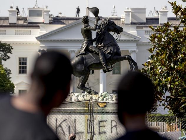 Statue of President Andrew Jackson on horseback, in Lafayette Square with the White House in the background and the word "KILLER" spray-painted on the statue's base