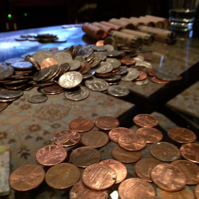 Photo of piles of US coins, with wrapped rolls of coins in the background