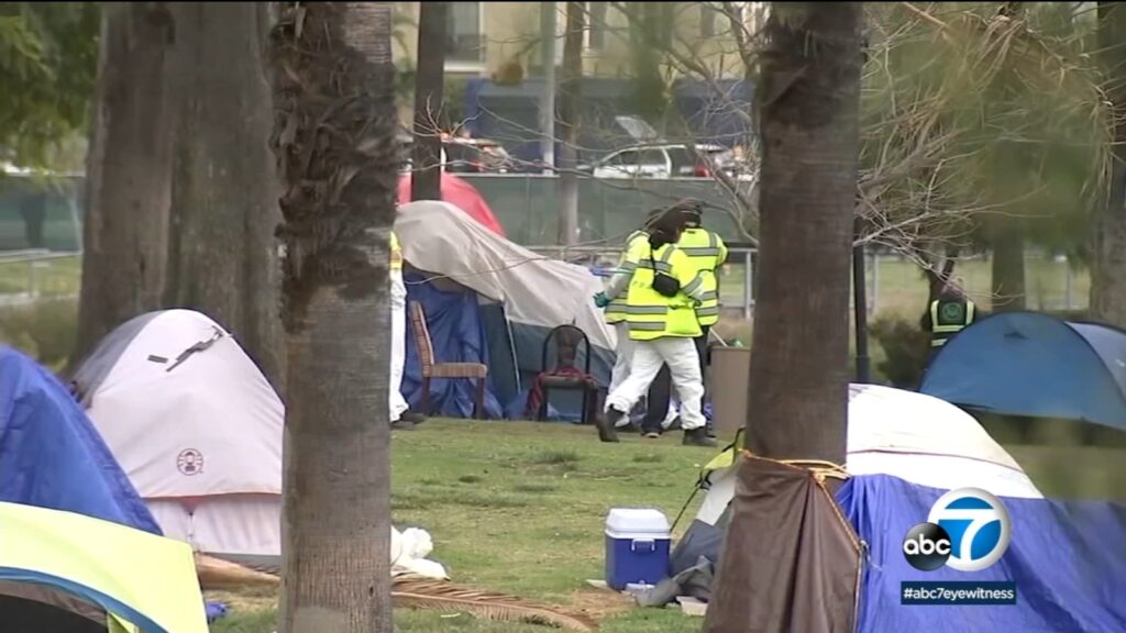 News photo of people in yellow vests clearing an encampment of people living in tents in Echo Park in Los Angeles