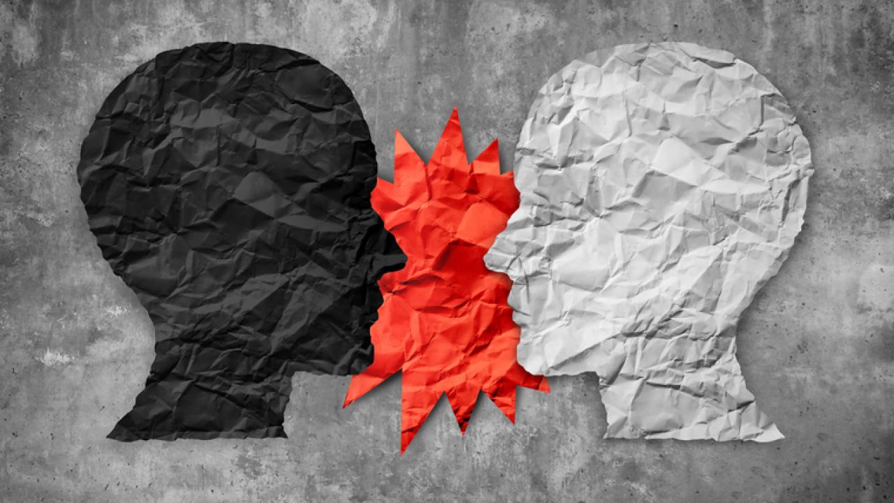 Image of two silhouetted heads, one black and one white, with an orange starburst in between them indicating speech or maybe conflict.