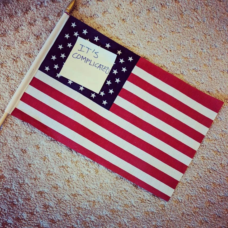 U.S. flag with a post-it on it saying "It's Complicated"