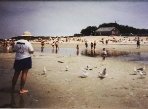 Old photo of a man on a beach with seagulls and children