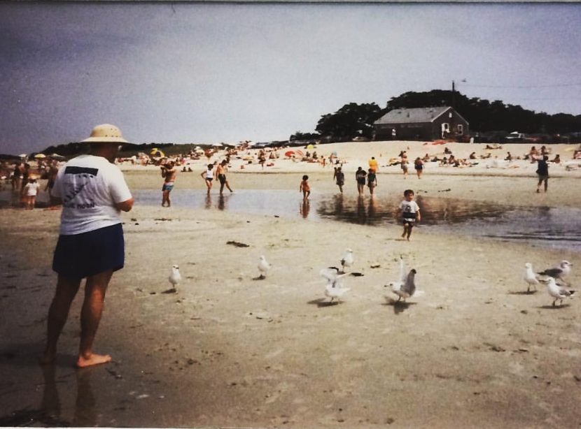 Old photo of a man on a beach with seagulls and children