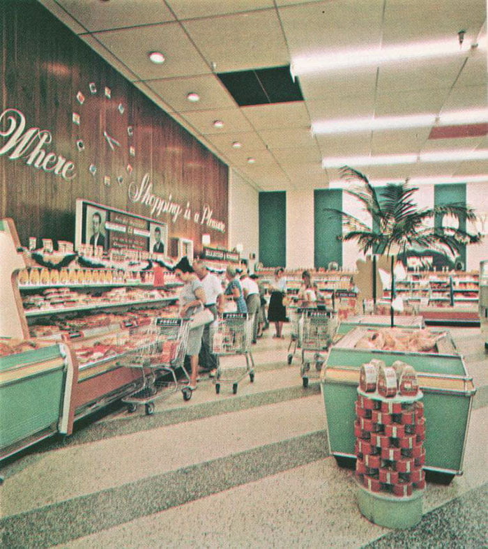 Pastel-toned vintage photo of a 1960s supermarket aisle filled with women and men pushing carts. A sign on the wood-paneled wall reads "Where Shopping is a Pleasure."